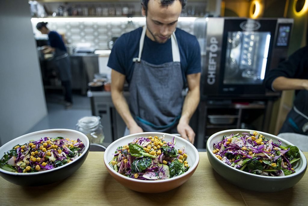 Cozinheiro a preparar três saladas coloridas para catering